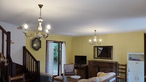 Un salon confortable avec un canapé, des fauteuils, un téléviseur et un meuble en bois.
