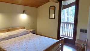 Une chambre avec deux lits, un plafond en bois, un miroir et une porte donnant sur un espace extérieur.