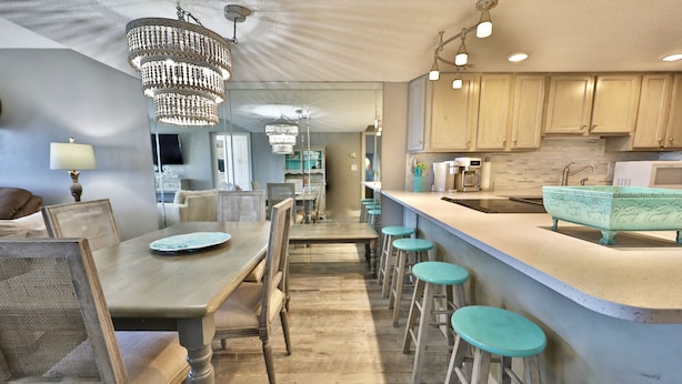 Een moderne keuken met een bar, houten barstoelen en een kroonluchter.