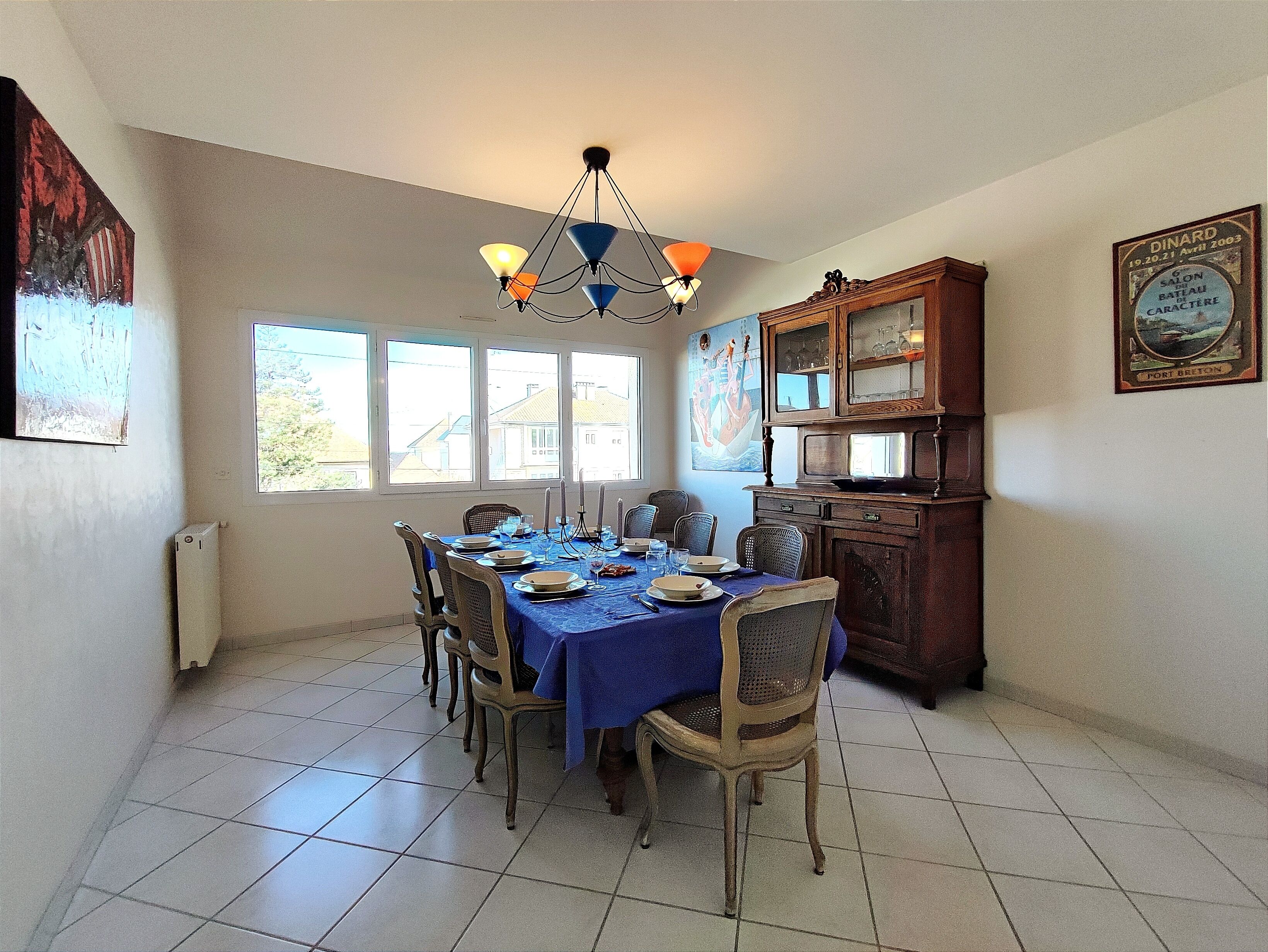 A dining room with a table set for six, a chandelier, and a cabinet with glass doors.