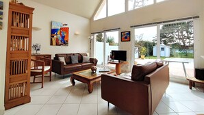 Un salón amplio con un gran ventanal, un mueble de madera, un sofá y una mesa de centro.