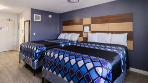 A hotel room with two beds, a wooden headboard, and a blue wall.