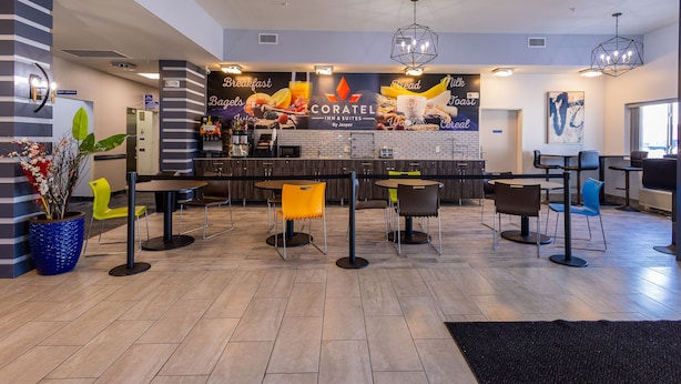 A modern hotel lobby with a breakfast bar, seating area, and a large mural advertising the hotel's breakfast offerings.