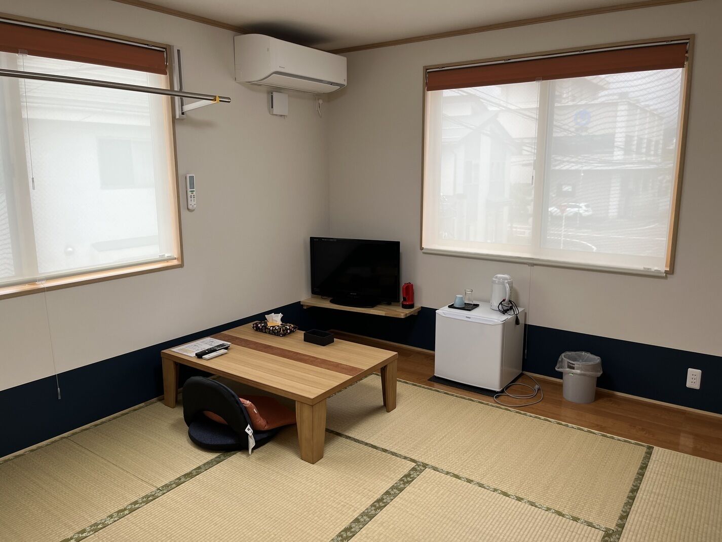 Una habitación pequeña con una cama, un escritorio, un televisor y una ventana.