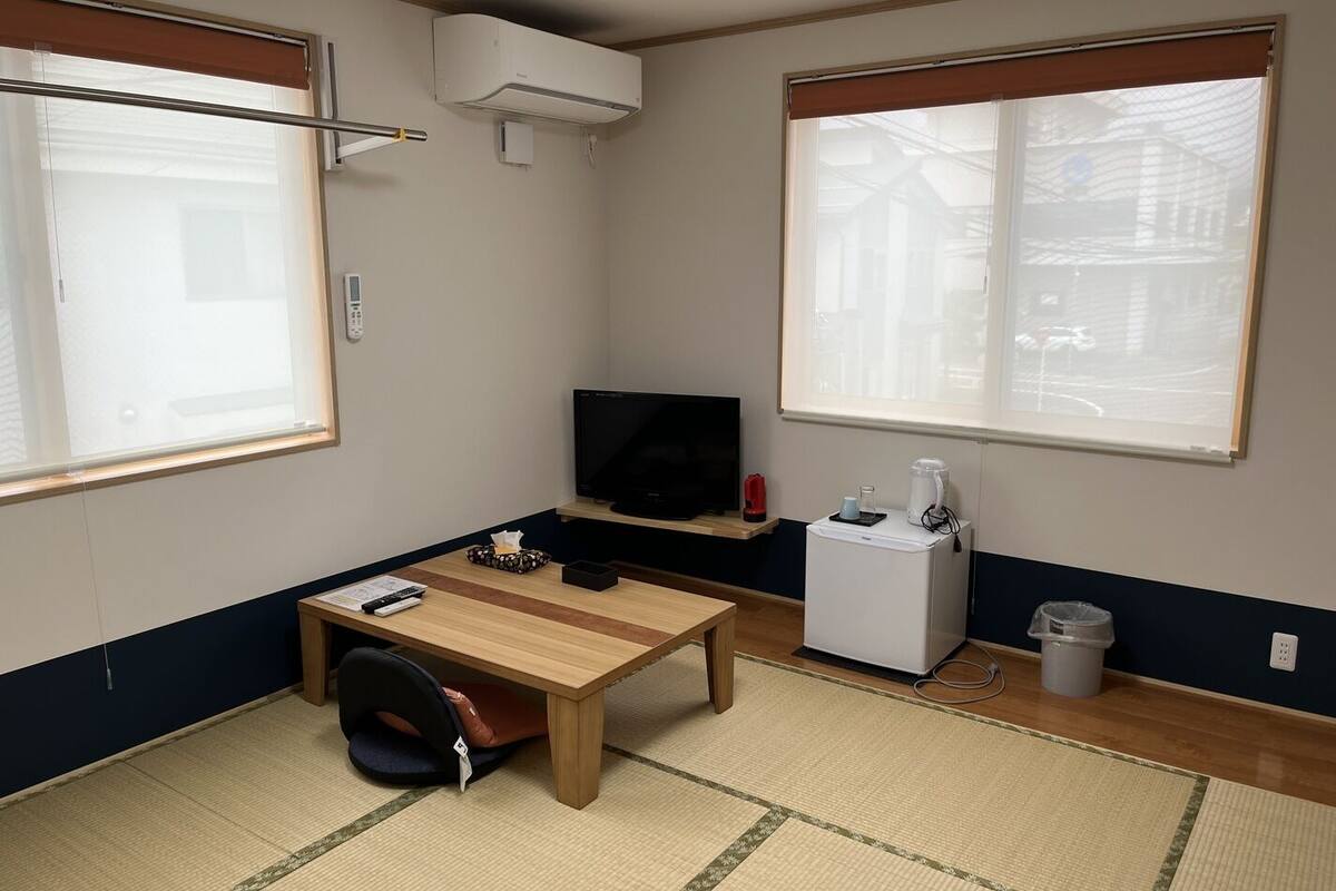 Una habitación pequeña con una cama, un escritorio, un televisor y una ventana.