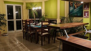 Un coin repas comprenant une table et des chaises en bois, une table à manger avec un plateau en verre, et une porte-fenêtre coulissante donnant sur un balcon.