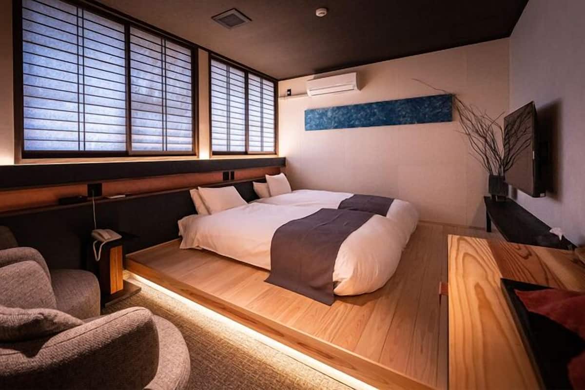 A modern bedroom with a large bed, a desk, a chair, and a TV.