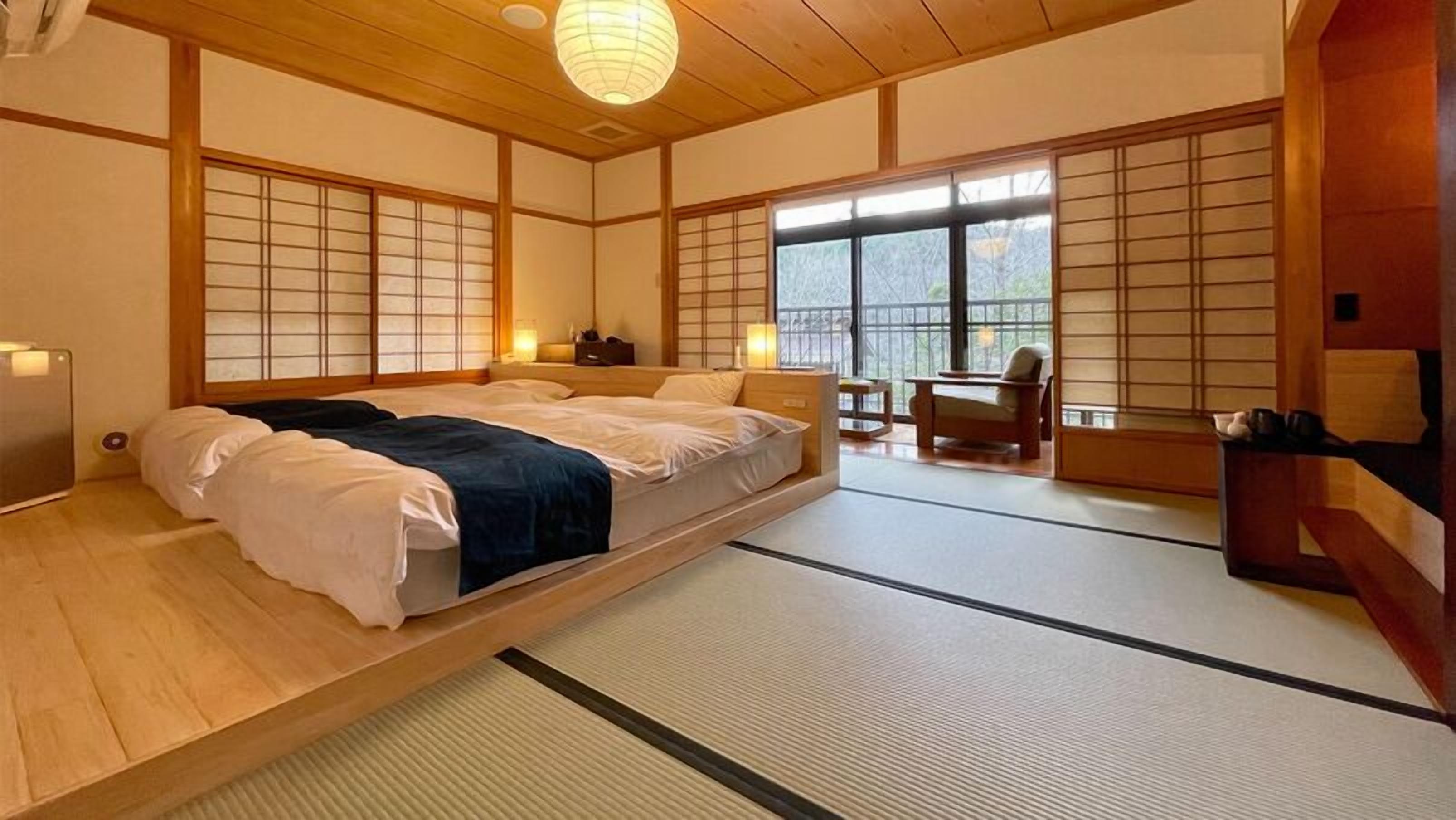 Una habitación tradicional japonesa con suelo de tatami, una cama baja sobre plataforma, puertas correderas shoji y vistas al exterior.