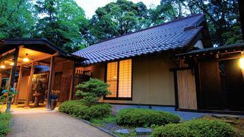 A traditional Japanese house with a tiled roof, wooden structure, and a garden area.