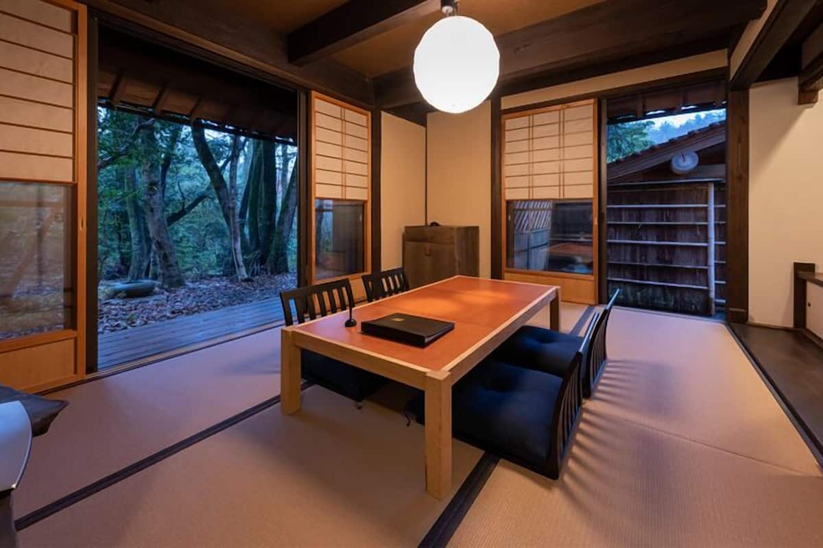 Una habitación tradicional japonesa con suelo de tatami, una mesa baja y puertas correderas.