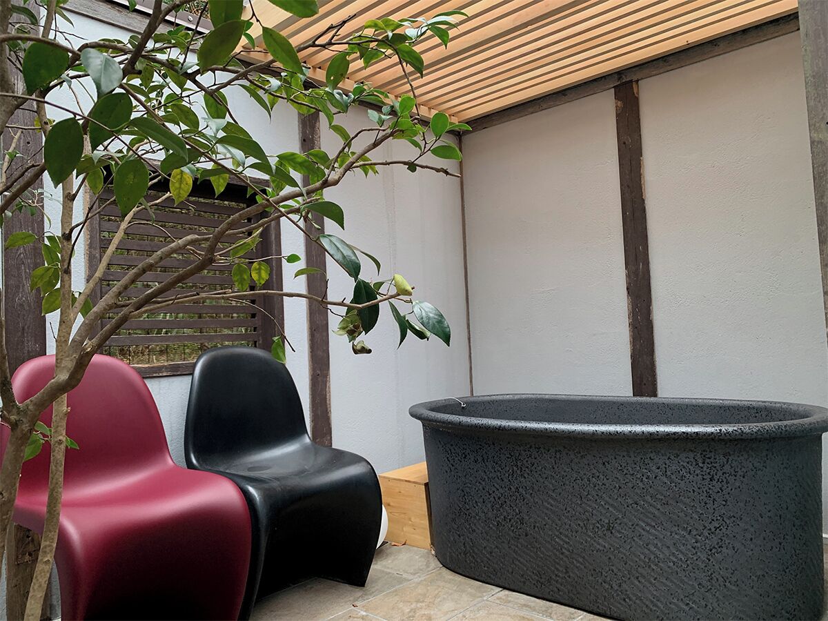 Un patio con dos sillas, una jardinera grande y una pérgola de madera.