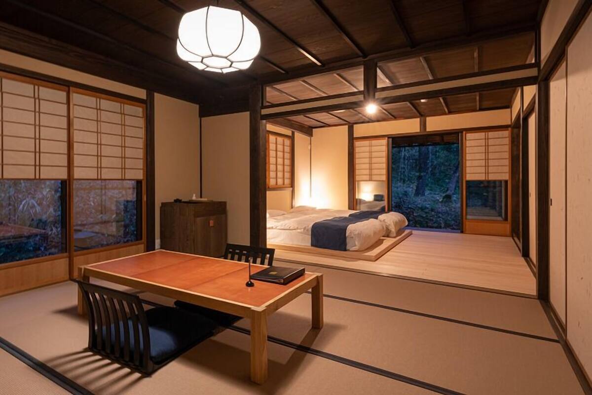 A traditional Japanese room with tatami flooring, a low table, a bed, and sliding doors.