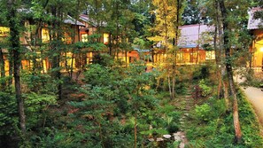 A forested area with traditional buildings, a clear path, and a small stream. - Arifuku Onsen Nushiya (Gotsu)