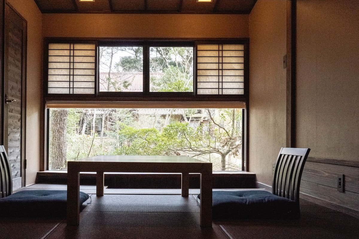 Una habitación japonesa tradicional con suelo de tatami, una mesa baja y puertas correderas shoji.