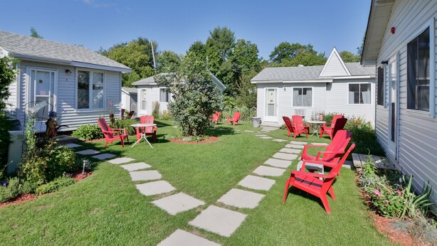 A residential area with two white mobile homes, red Adirondack chairs, and a well-maintained lawn with stepping stones. - Oakwood Motel (Gravenhurst)