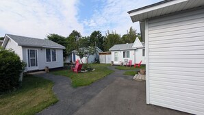 A row of mobile homes with a paved walkway and red chairs in the yard. - Oakwood Motel (Gravenhurst)