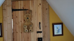 Una puerta de madera con un recorte de oso, una señal de flecha negra y un cuadro en la pared.