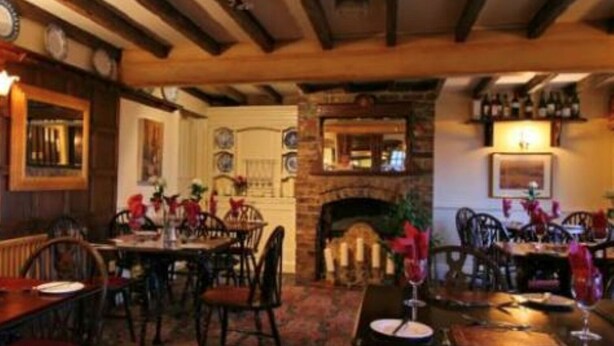 Un restaurante acogedor con vigas de madera, chimenea de ladrillo y decoración tradicional.