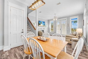 Relax in this inviting living area with a dining table, comfortable sofa, and large window offering a view of palm trees.