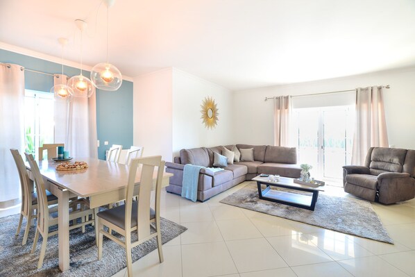 A modern living room with a dining area, a sectional sofa, and a coffee table. - Spacious, modern villa with private swimming pool and sea view (Carvoeiro)