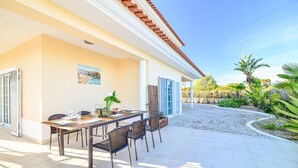 A patio with a table set for dining, chairs, and a decorative plant.