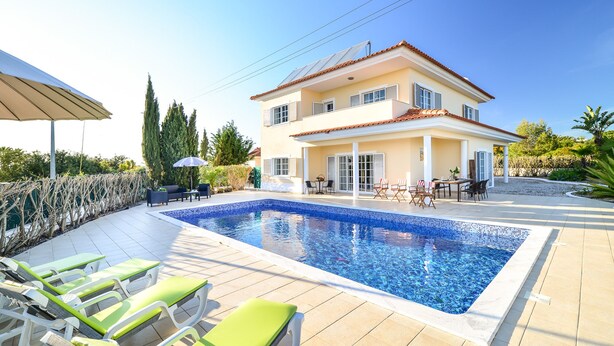 A two-story house with a swimming pool, outdoor seating, and a garden.