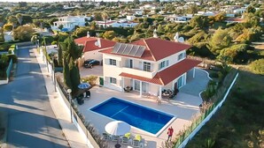 A two-story house with a swimming pool, solar panels, and a view of the surrounding neighborhood.