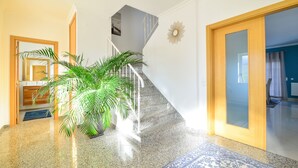 A staircase with a handrail, a potted plant, and a blue patterned rug.