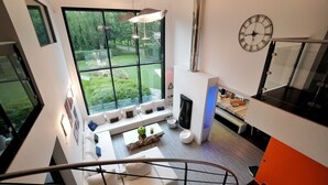 Un intérieur moderne avec une grande fenêtre, un escalier et un espace de vie comprenant un canapé et une table basse.