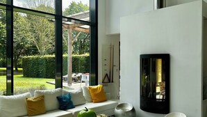 Un salon moderne avec une table basse en verre, des canapés blancs et une cheminée.