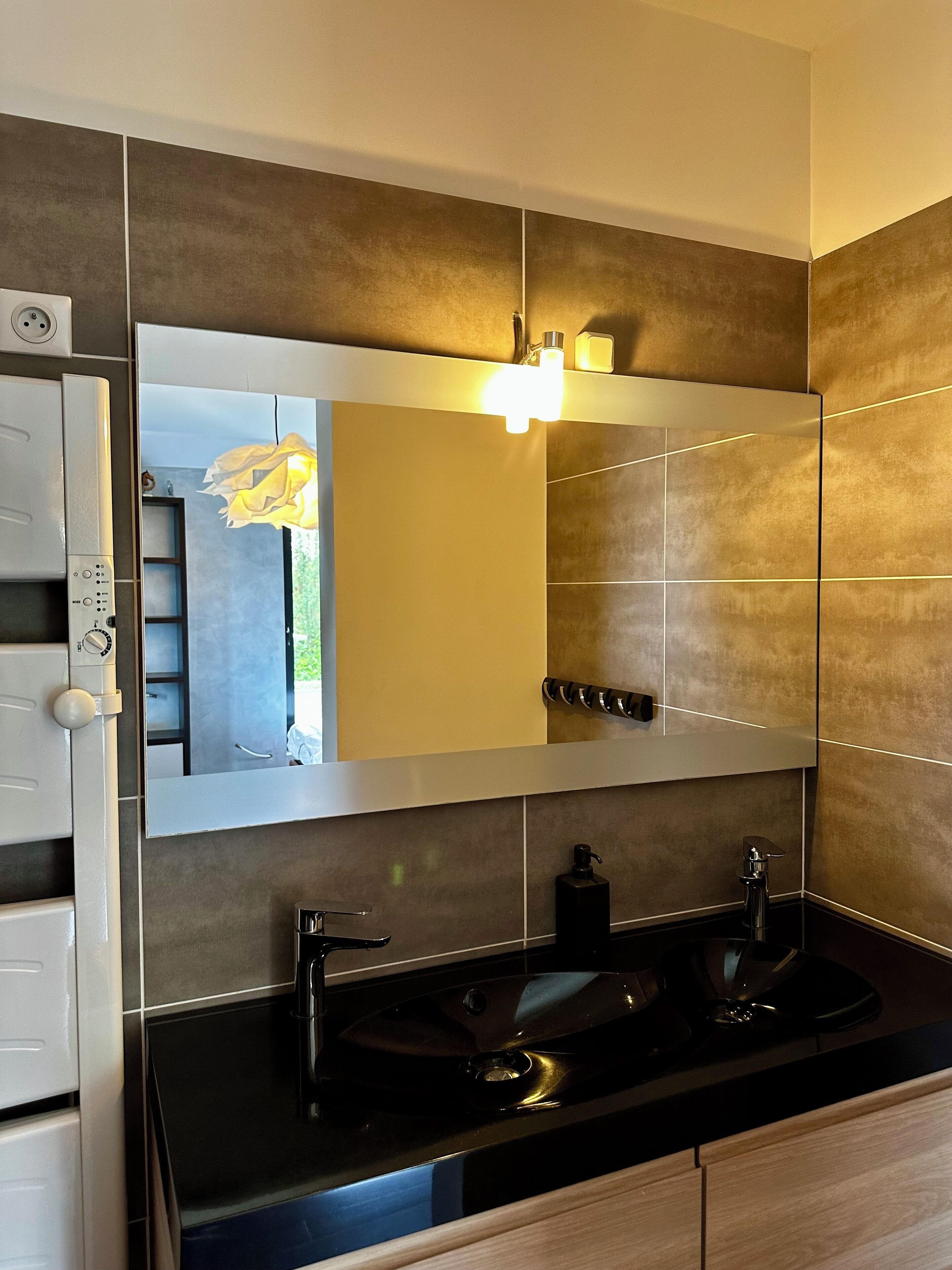 A modern bathroom with a large mirror, two sinks, and a towel rack.