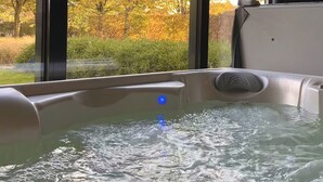 Un bain à remous avec vue sur les arbres aux couleurs automnales, grâce à de grandes fenêtres.