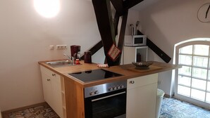 Una cocina compacta con estufa, horno y lavamanos integrados. Cuenta con encimera de madera y suelo de baldosas con estampado.
