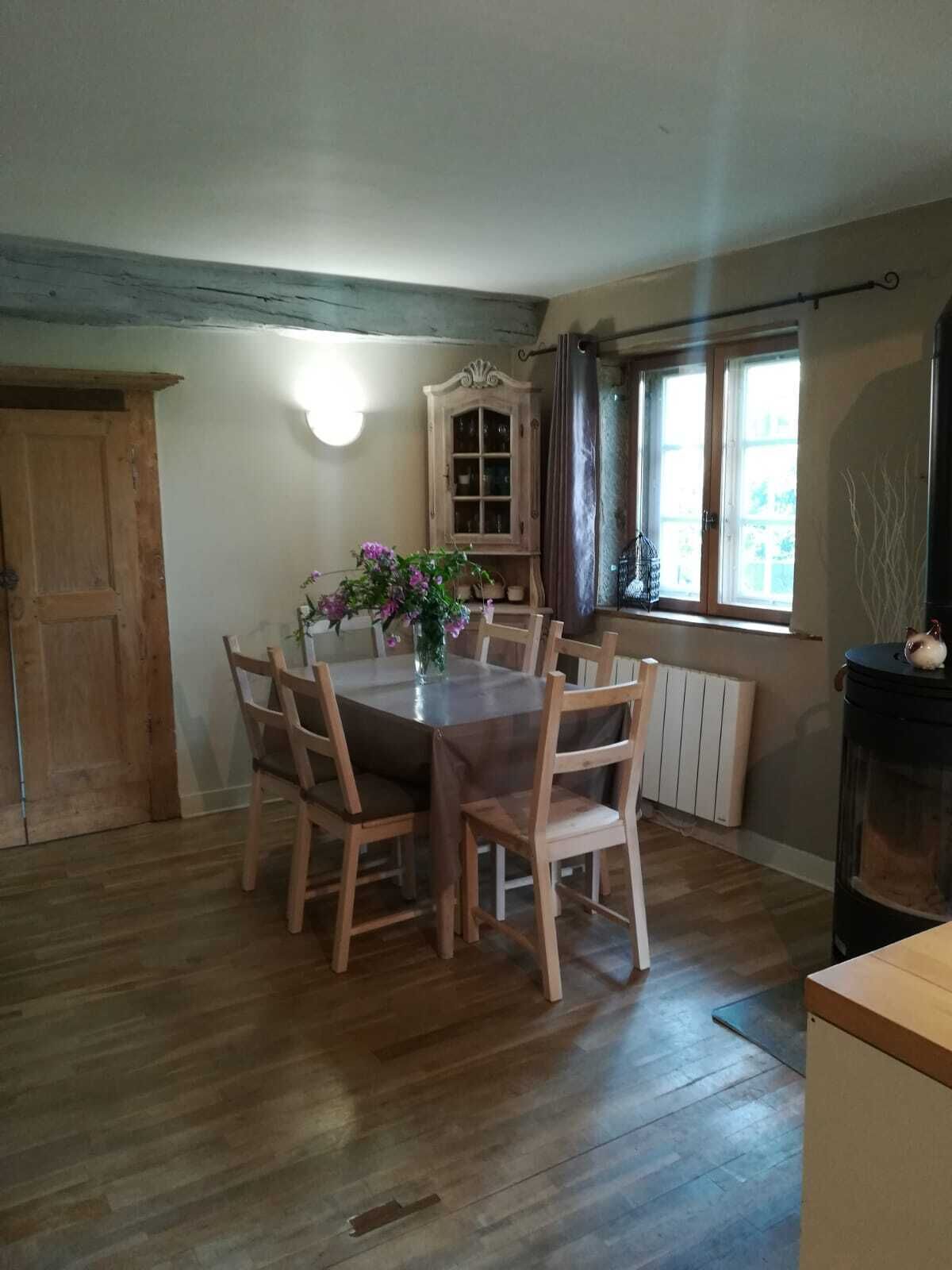 Un coin repas avec une table ronde, des chaises en bois, un buffet et une fenêtre avec des rideaux.