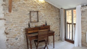 Una stanza con parete in pietra, una scrivania e una sedia in legno.