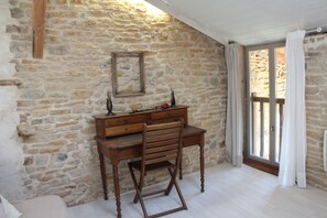 Une pièce avec un mur en pierre, un bureau en bois et une chaise.