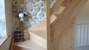 Una scala in legno con uno sfondo di parete in pietra, una lampada e un pavimento in legno.