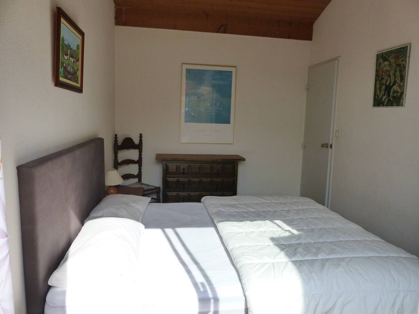 Une chambre à coucher avec un lit, une commode, une chaise et une porte.