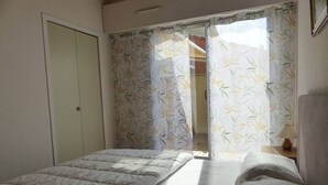 Un dormitorio con cama, armario y ventana con cortinas de estampado de bambú.