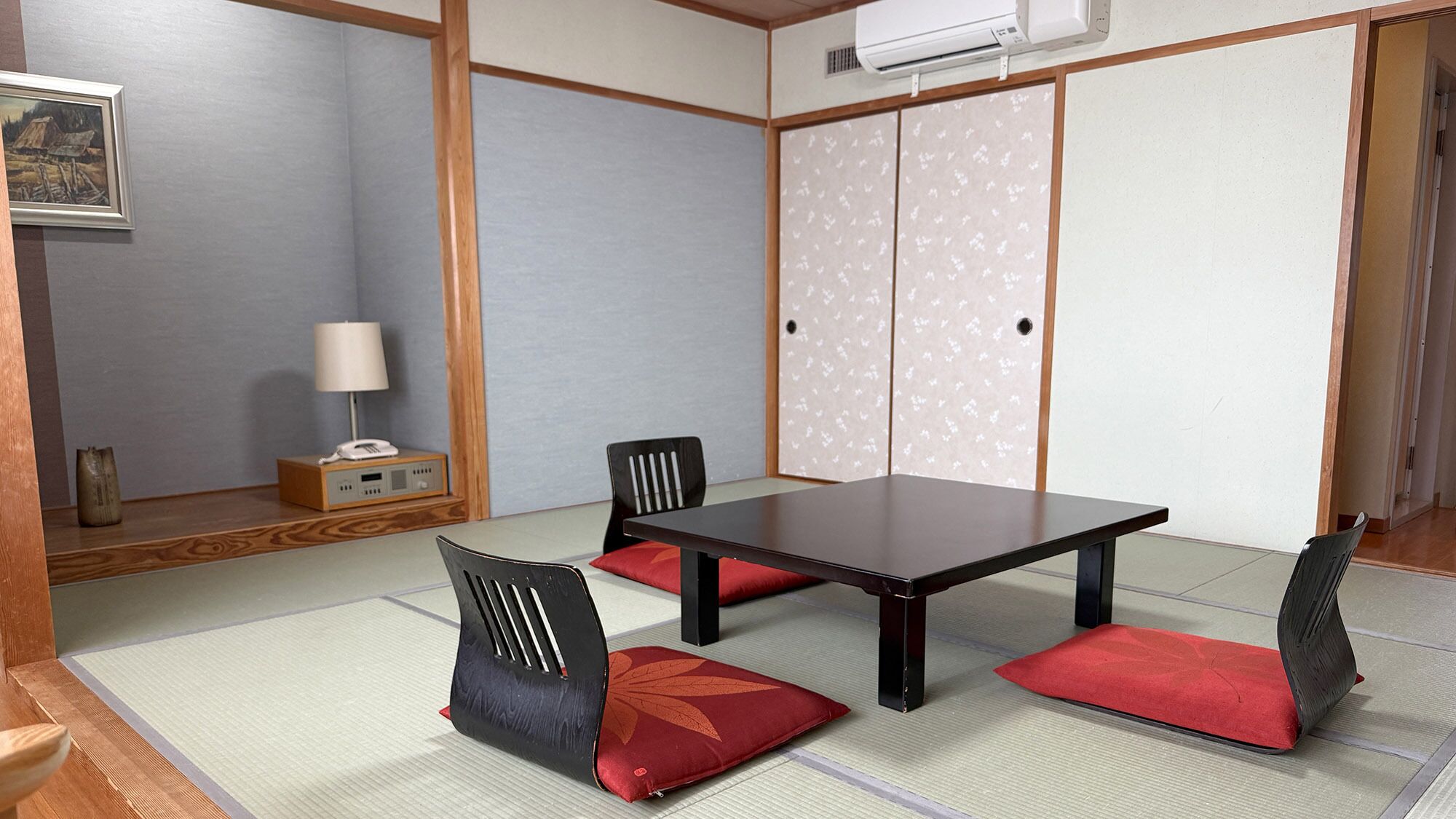 Una habitación japonesa tradicional con suelo de tatami, una mesa baja y paneles shoji.