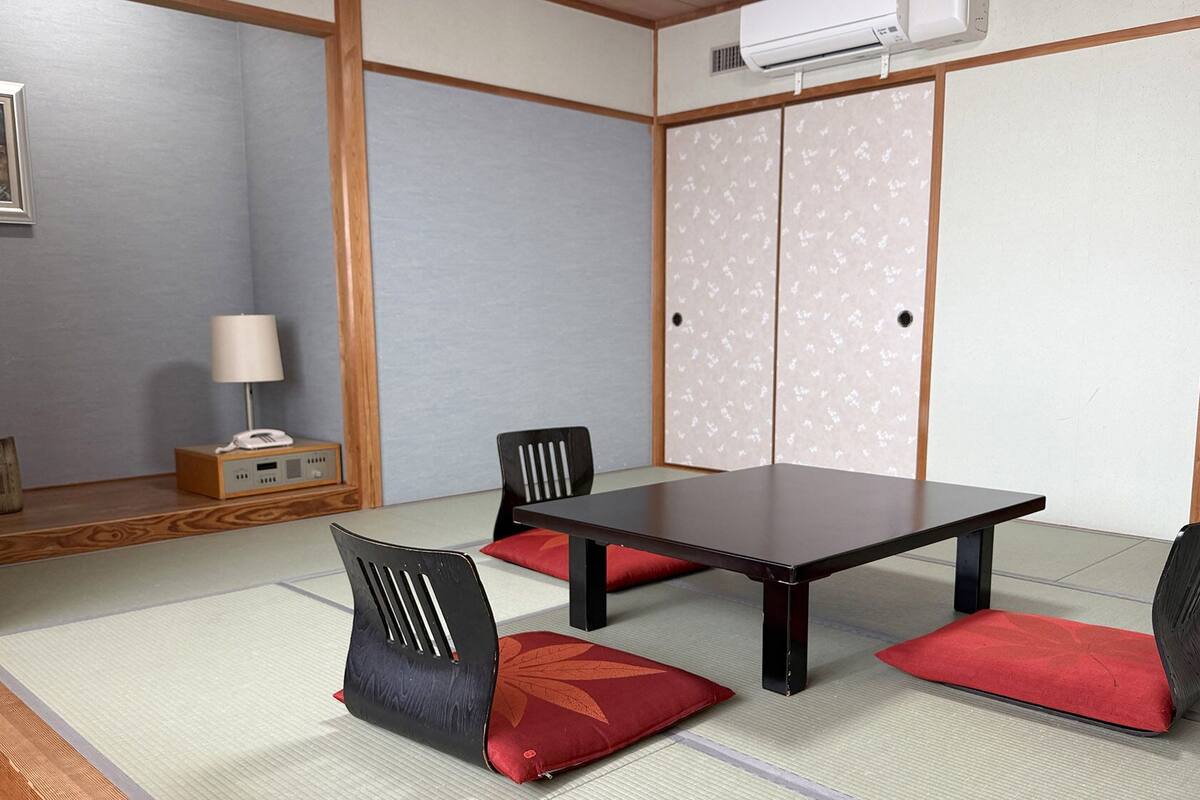 Una habitación japonesa tradicional con suelo de tatami, una mesa baja y paneles shoji.