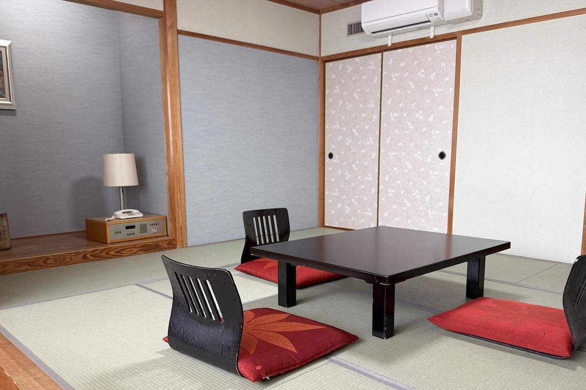 Una habitación japonesa tradicional con suelo de tatami, una mesa baja y paneles shoji.