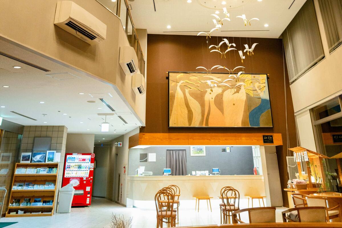 Un vestíbulo de hotel con una lámpara de araña moderna, una recepción y una zona de estar.