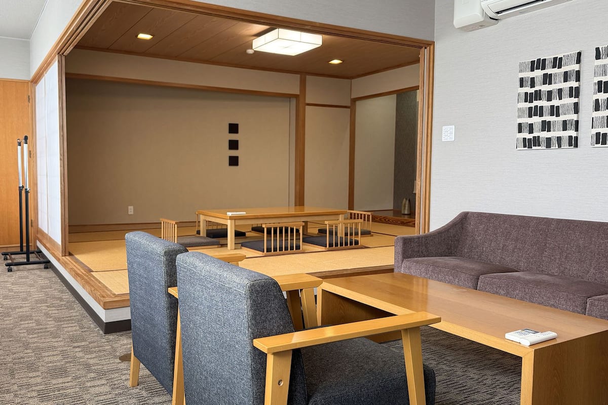 Huone, jossa on tatami-matto lattialla, matala puupöytä, sohva ja perinteinen japanilainen liukuovi.