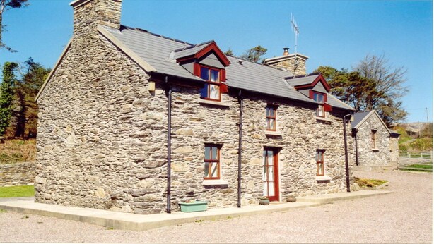 A stone building with a gabled roof, multiple windows, and a chimney. - Pine Cottage - Sheeps Head Peninsula (Bantry)