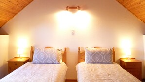 A room with two beds, wooden headboards, and bedside lamps. - Pine Cottage - Sheeps Head Peninsula (Bantry)