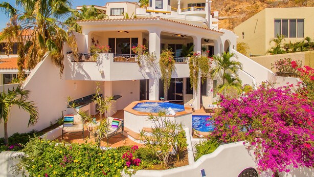A multi-story house with a pool, outdoor seating, and lush landscaping. - Pedregal Villa w/ Pool, Hot Tub, Walk to Town, Near Swim Beach & Ocean Views (Cabo San Lucas)