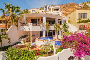 A multi-story house with a pool, outdoor seating, and lush landscaping.