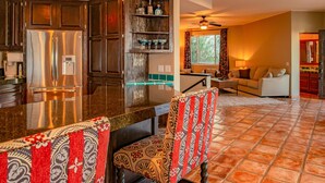 A modern kitchen with a stainless steel refrigerator, wooden cabinets, and a built-in bar area. - Pedregal Villa w/ Pool, Hot Tub, Walk to Town, Near Swim Beach & Ocean Views (Cabo San Lucas)
