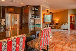 A modern kitchen with a stainless steel refrigerator, wooden cabinets, and a built-in bar area.